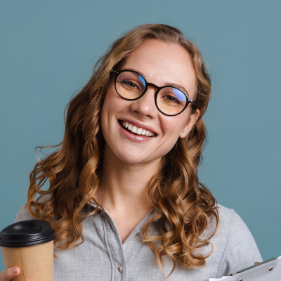 young blonde woman with glasses smiling and holding cup of coffee